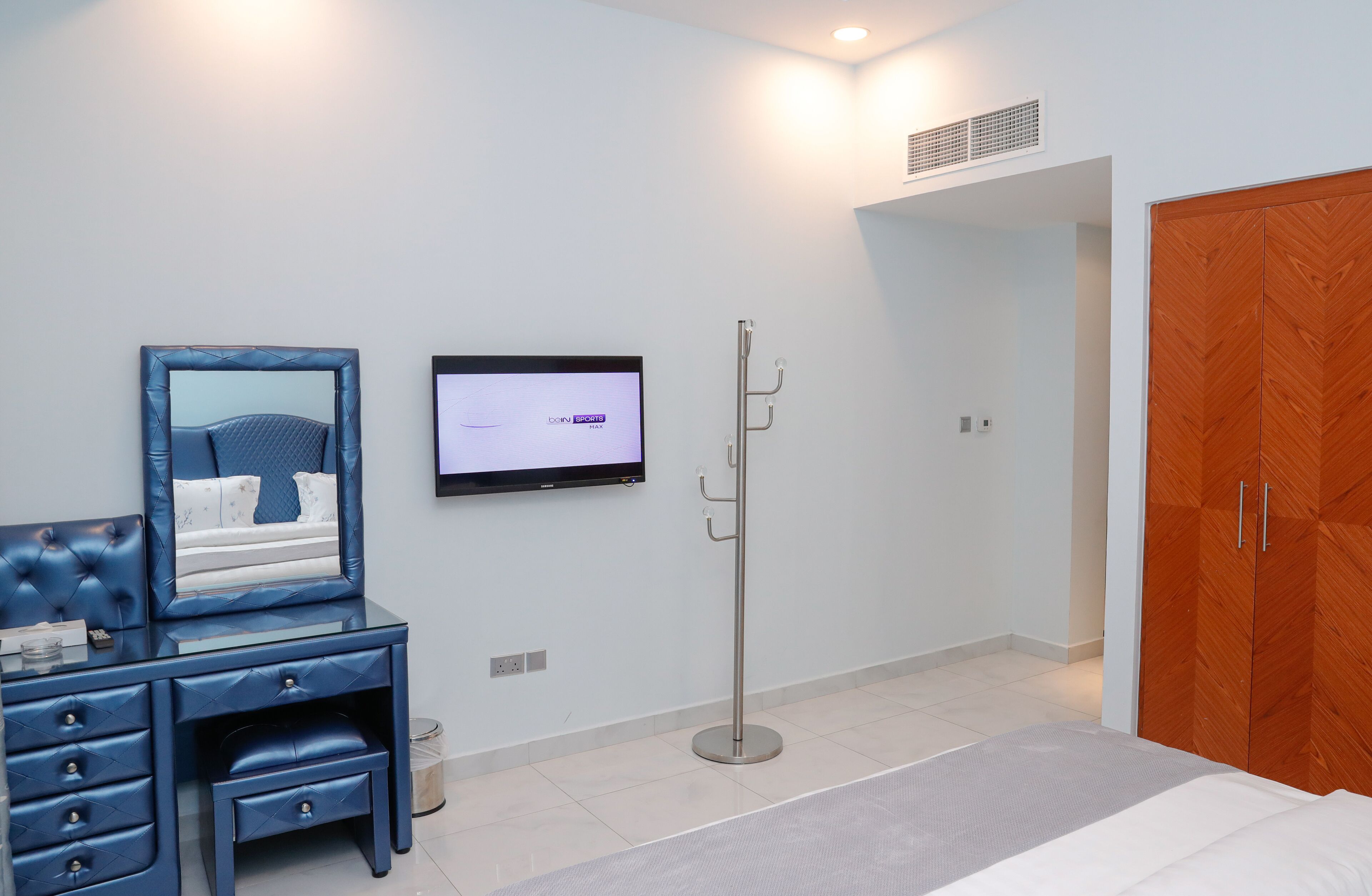 Une chambre à coucher comprenant un lit, une télévision, une armoire et un bureau avec des tiroirs.