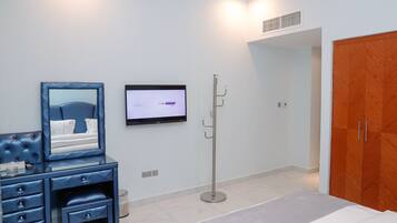 Une chambre à coucher comprenant un lit, une télévision, une armoire et un bureau avec des tiroirs.