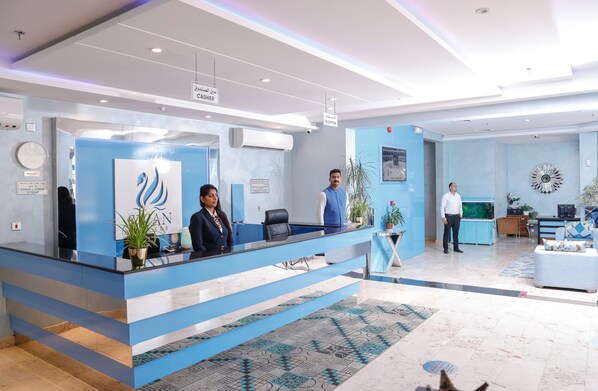Un área de recepción moderna con mostrador azul, un reloj y una mesa de recepción.