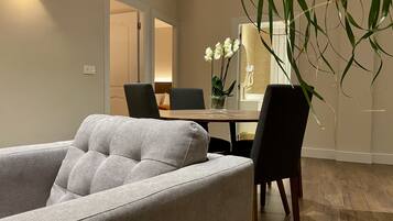 Un salon moderne avec un canapé gris, une table à manger avec des chaises et une plante en pot.