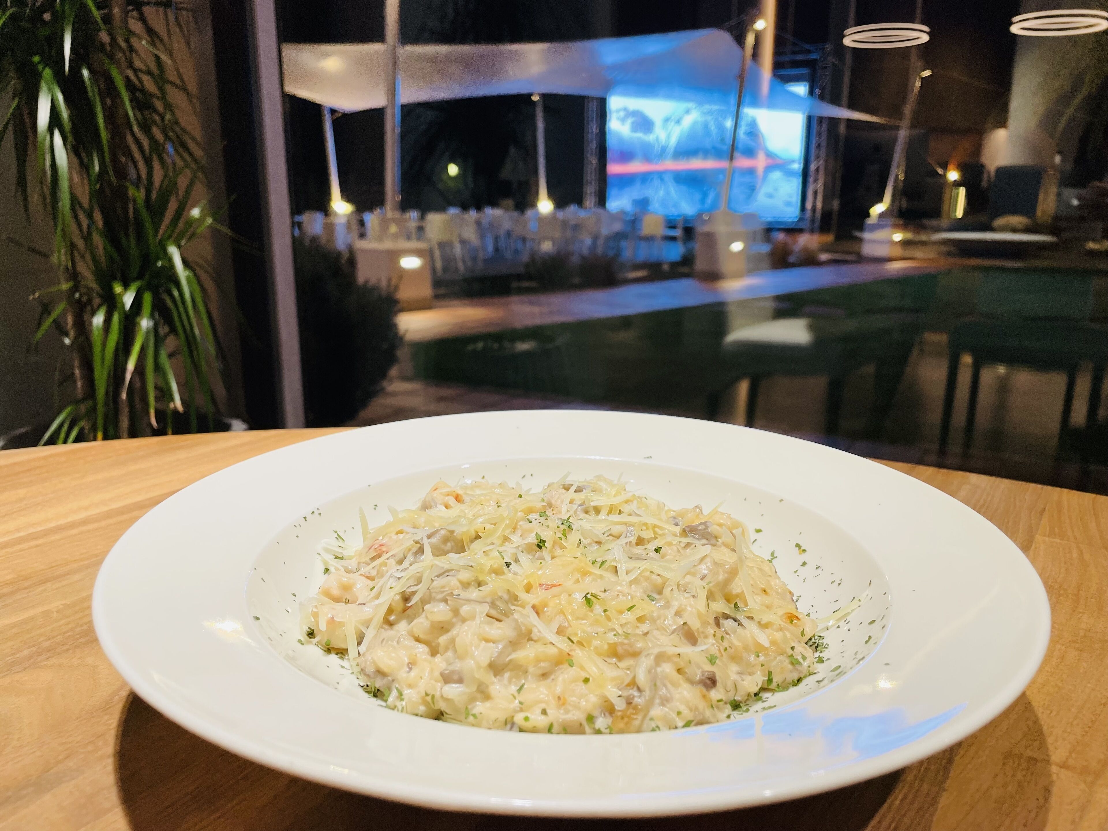 A plate of pasta with a creamy sauce, garnished with herbs, on a wooden table.