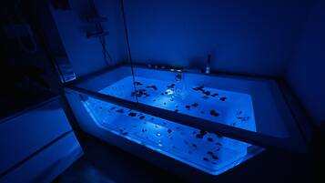 Una bañera con cerramiento de vidrio y luz azul.