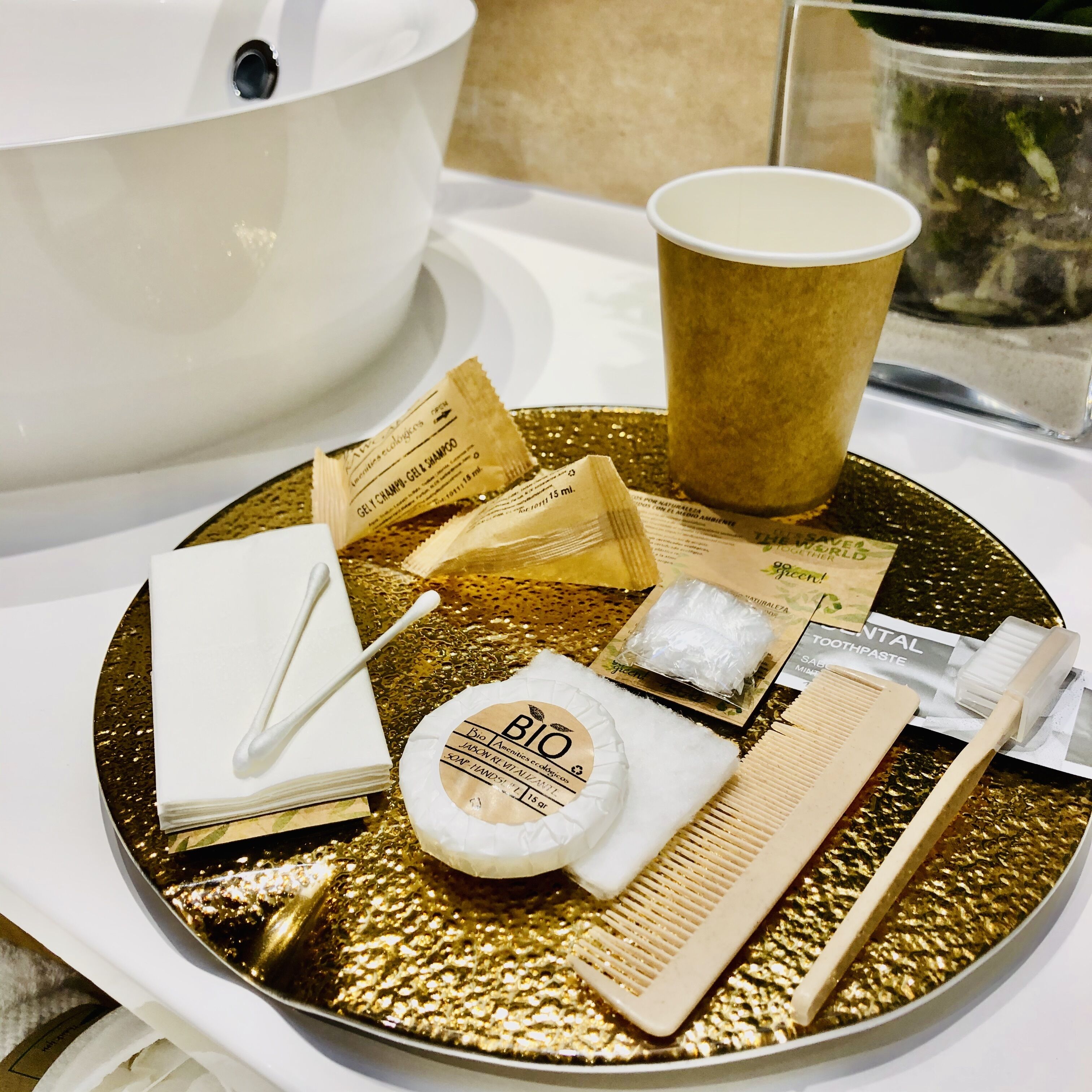 Un plateau contenant des articles de toilette, notamment un peigne, une brosse à dents, un gobelet et une bouteille de shampoing.