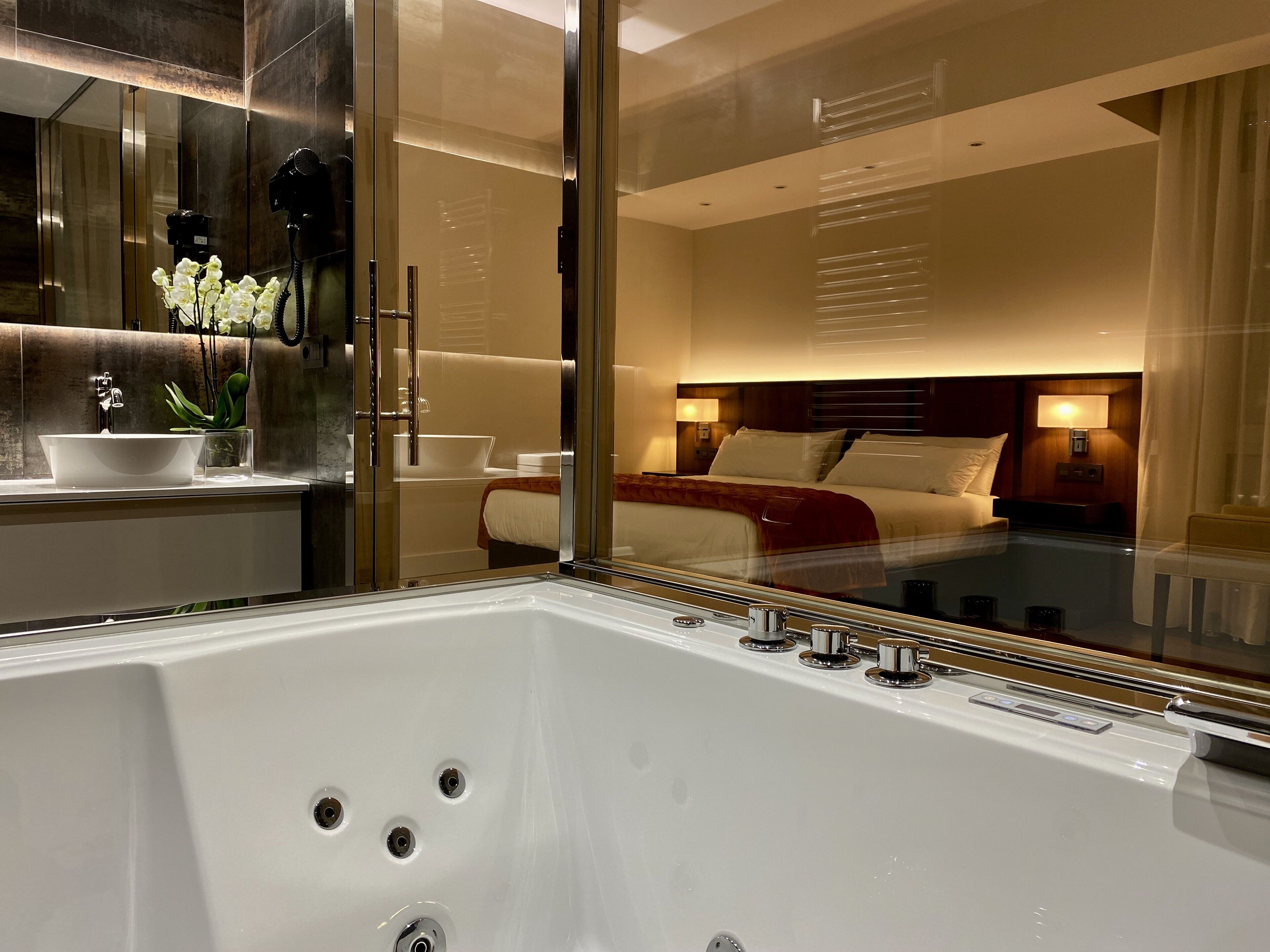 A modern hotel bathroom with a large bathtub, a glass-enclosed shower, and a vanity with a sink and mirror.