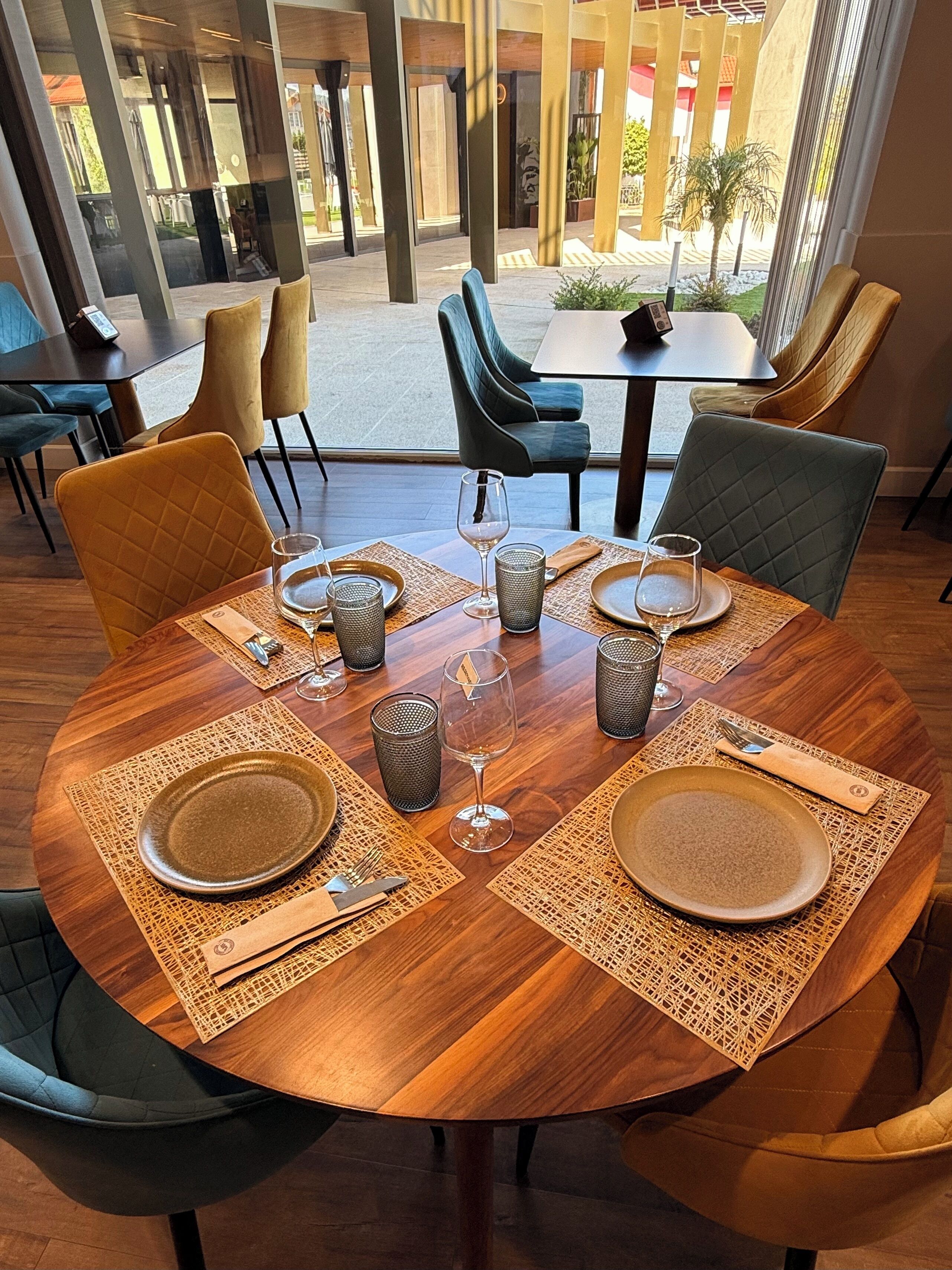 A dining area with round tables, chairs, and a view of the outdoor patio.