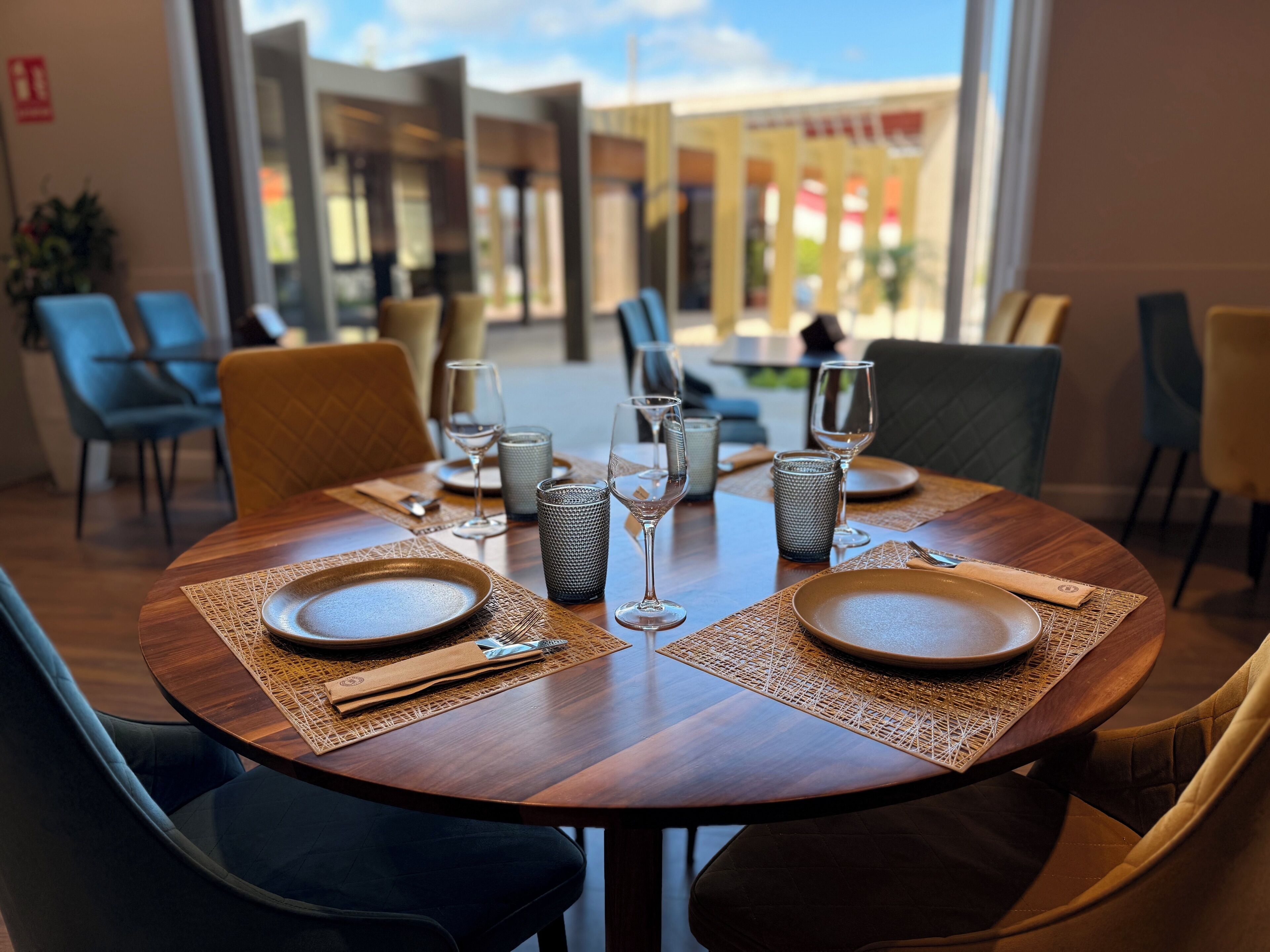 A dining area with round tables set for two, each with plates, cutlery, and glasses.