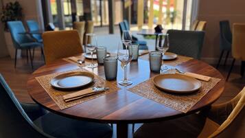 A dining area with round tables set for two, each with plates, cutlery, and glasses.