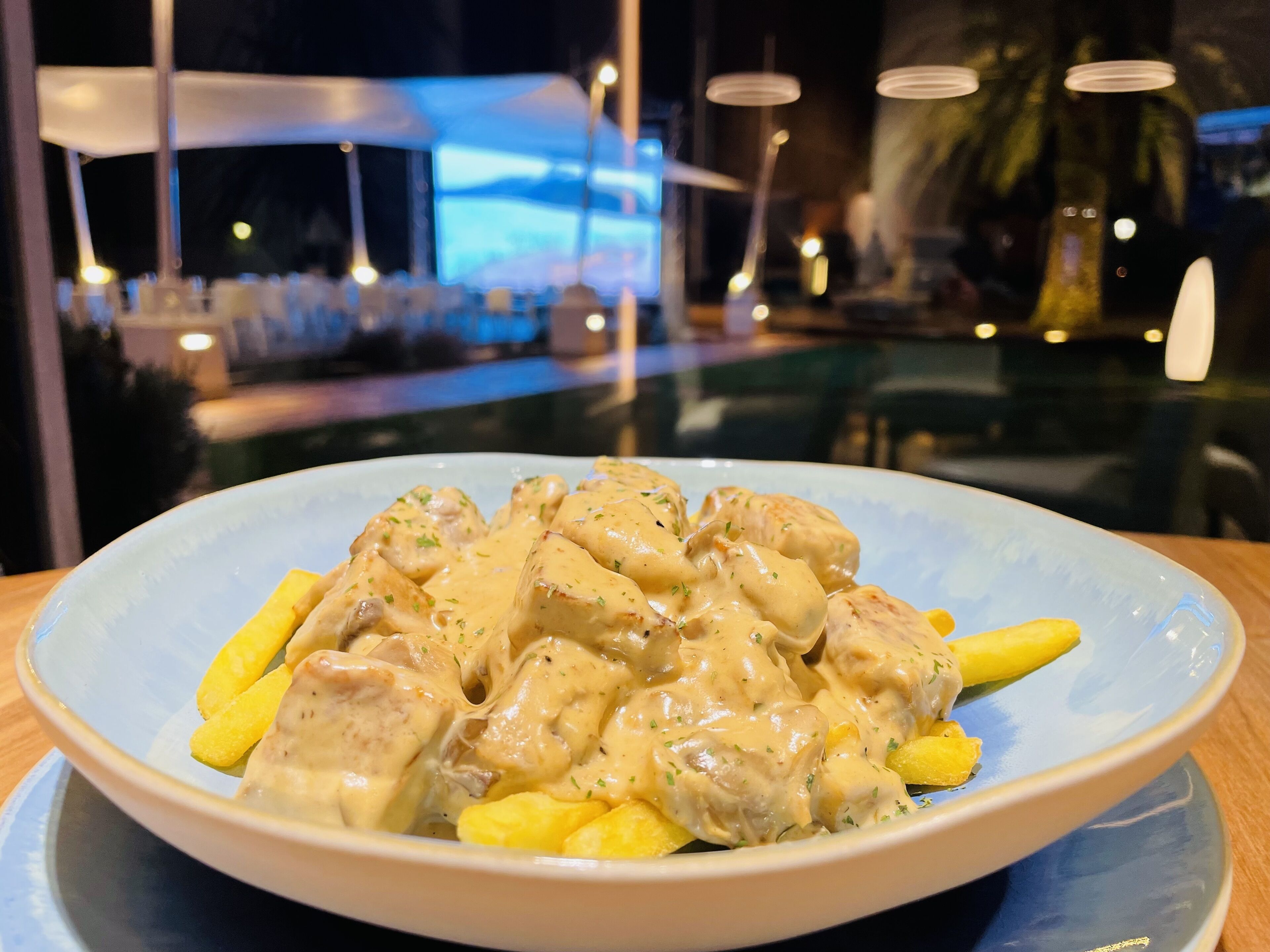 A plate of food with creamy sauce and herbs, served on a blue plate.