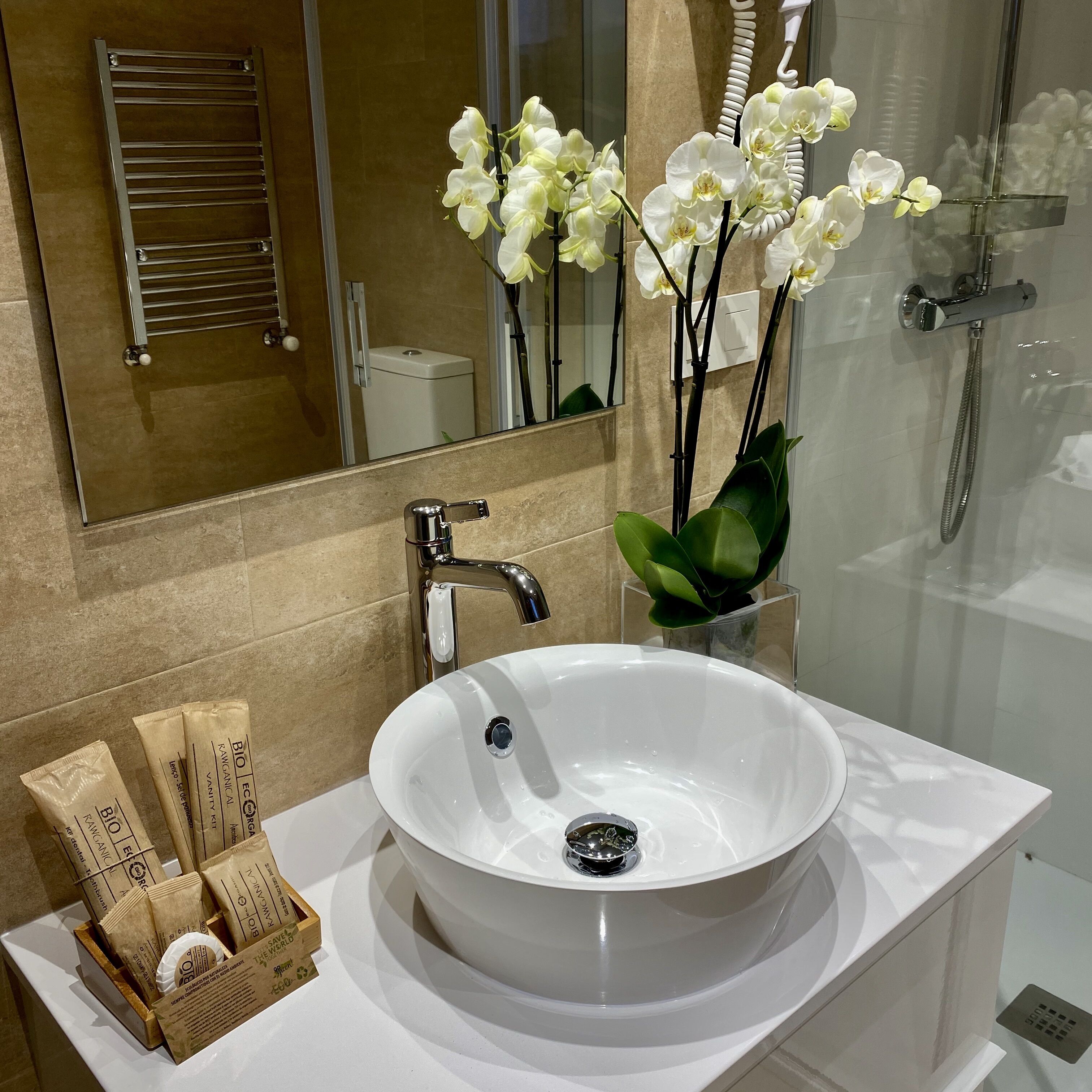 Un baño moderno con un lavamanos blanco, un espejo y una ducha.