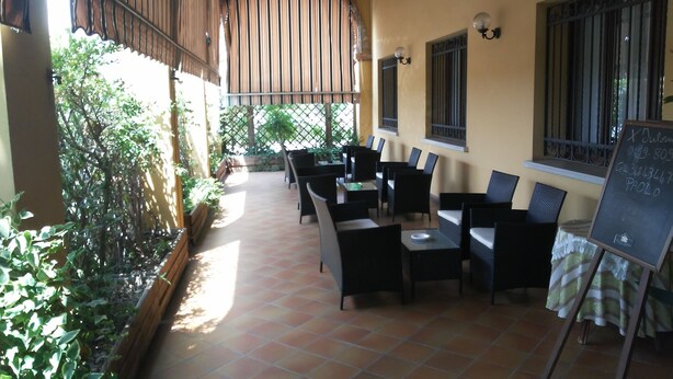 An outdoor patio with tiled flooring, black wicker furniture, and a chalkboard sign. - Albergo Ristorante La Campagnola (Urbana)