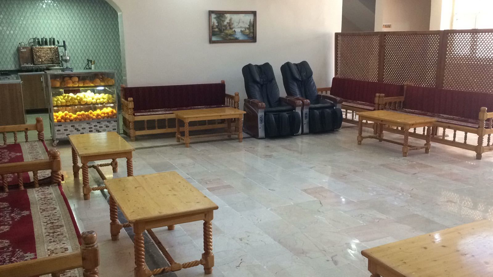 A room with wooden furniture, including tables and benches, a tiled floor, and a decorative wall with a painting.