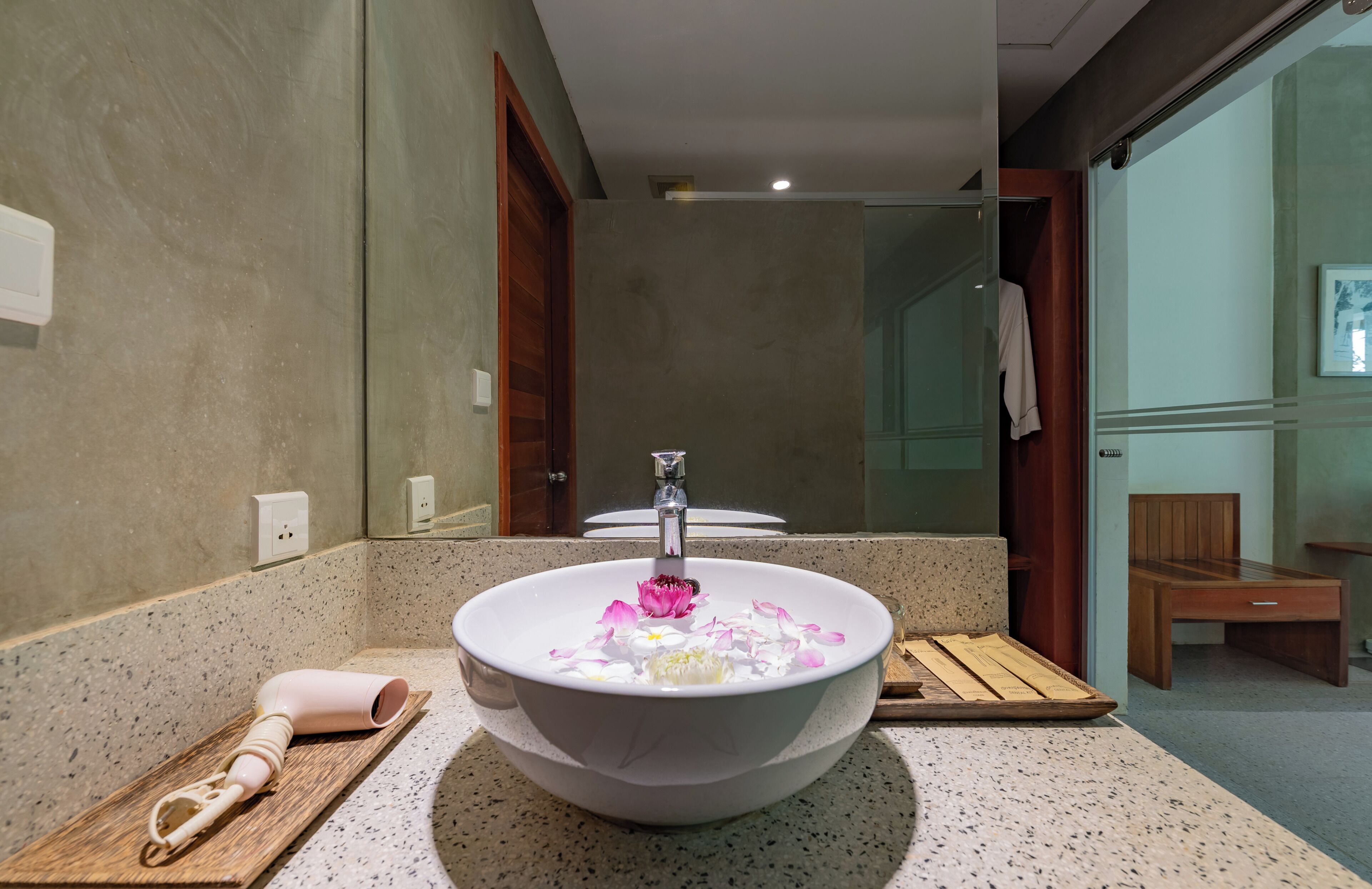 Un baño con un lavamanos tipo cuenco grande, un banco de madera, una toalla y un espejo.