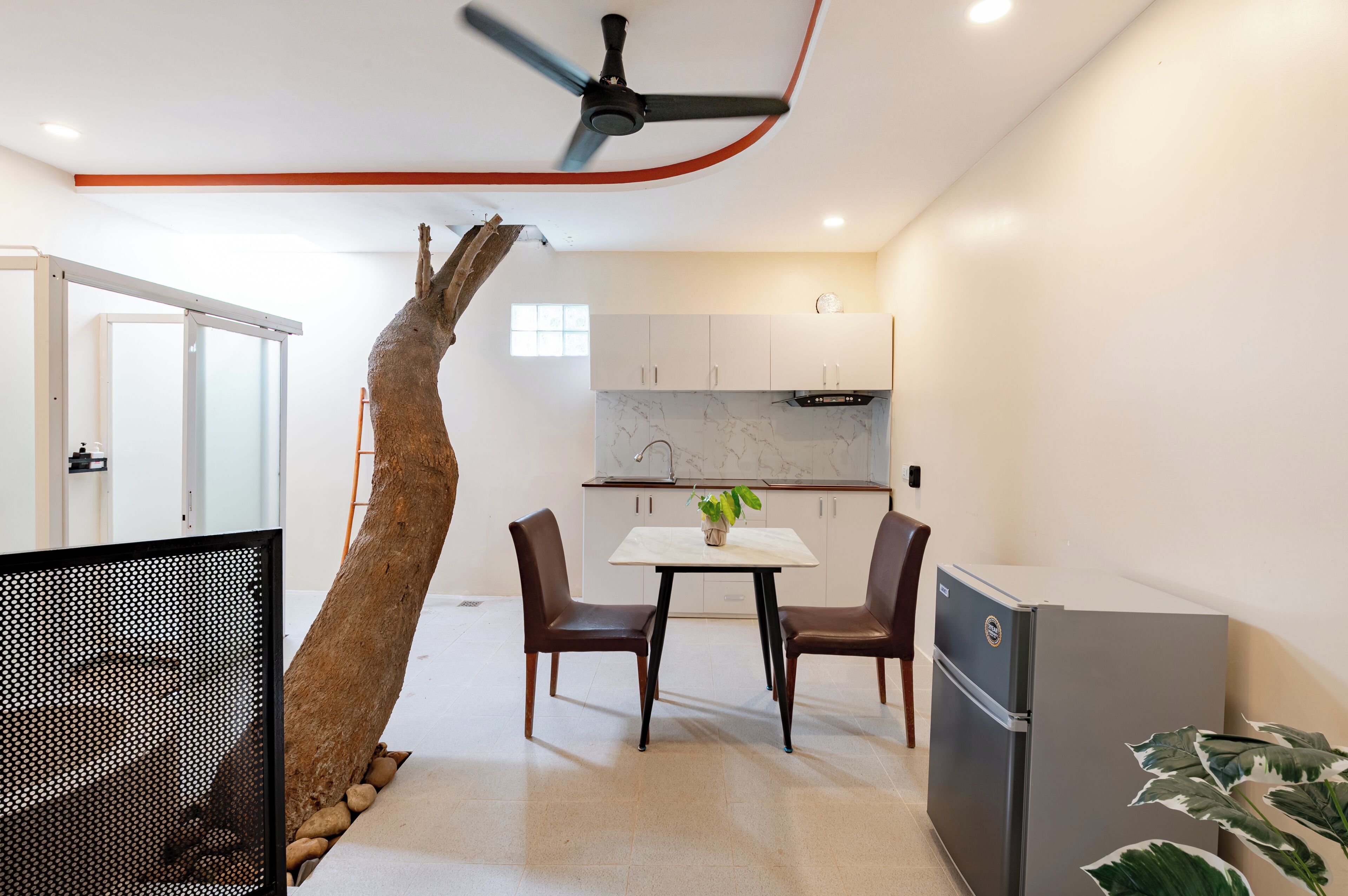 A modern kitchen with white cabinets, a marble backsplash, and a dining area with a table and chairs.