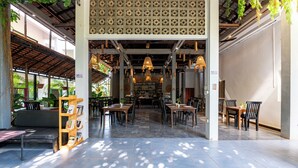 A spacious indoor area with tables and chairs, a bookshelf, and hanging plants. - Tanei Angkor Resort and Spa (Siem Reap)