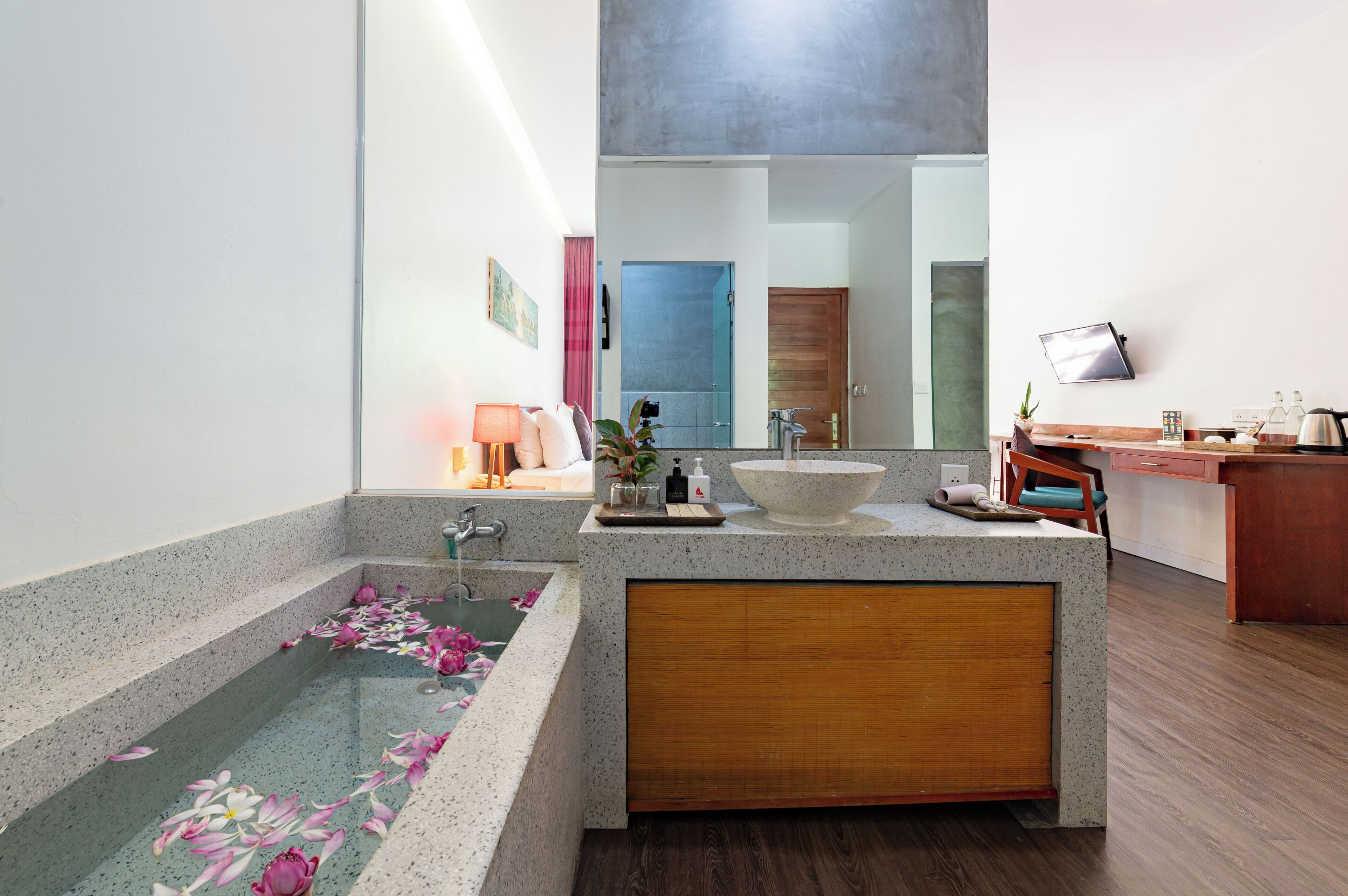 A modern bathroom with a freestanding bathtub, a large mirror, and a wooden vanity.
