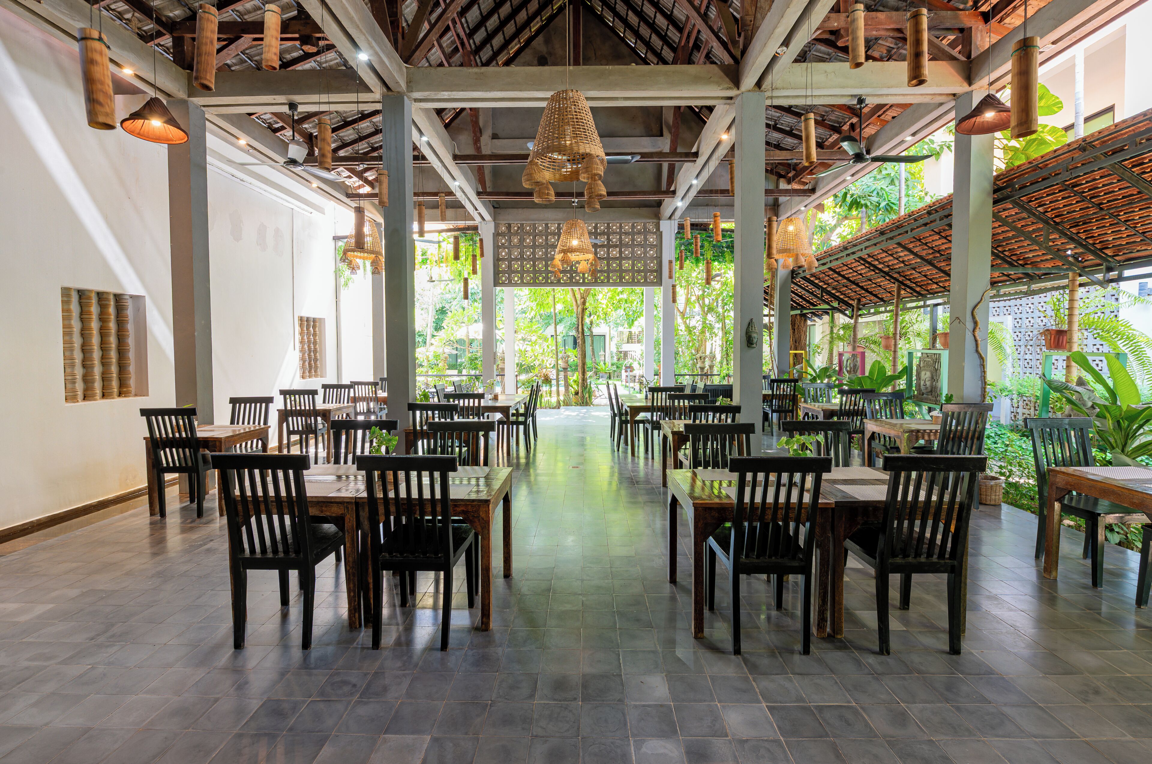An indoor dining area with wooden tables and chairs, a central walkway, and hanging light fixtures.