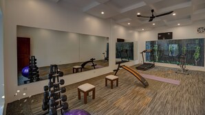 A modern gym with a mirrored wall, ceiling fan, and exercise equipment. - Tanei Angkor Resort and Spa (Siem Reap)