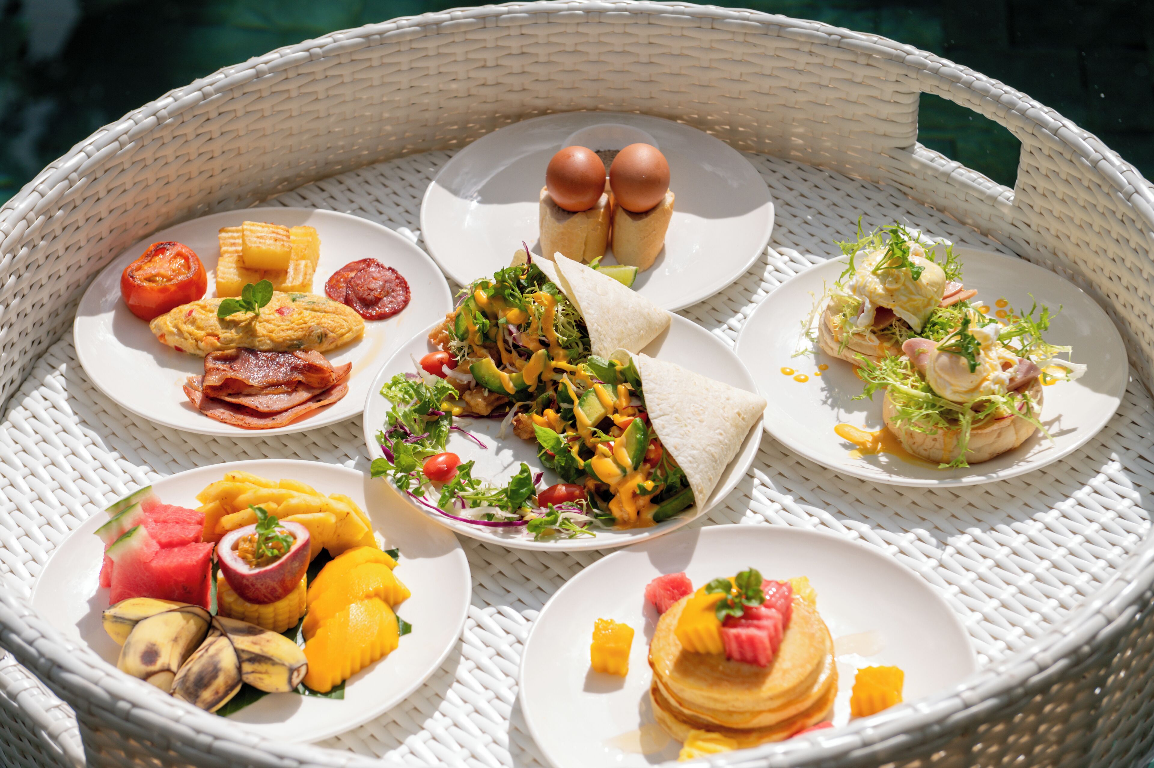 Un panier en osier contenant divers aliments pour le petit-déjeuner, notamment des œufs, du bacon, des toasts, une salade et des fruits.