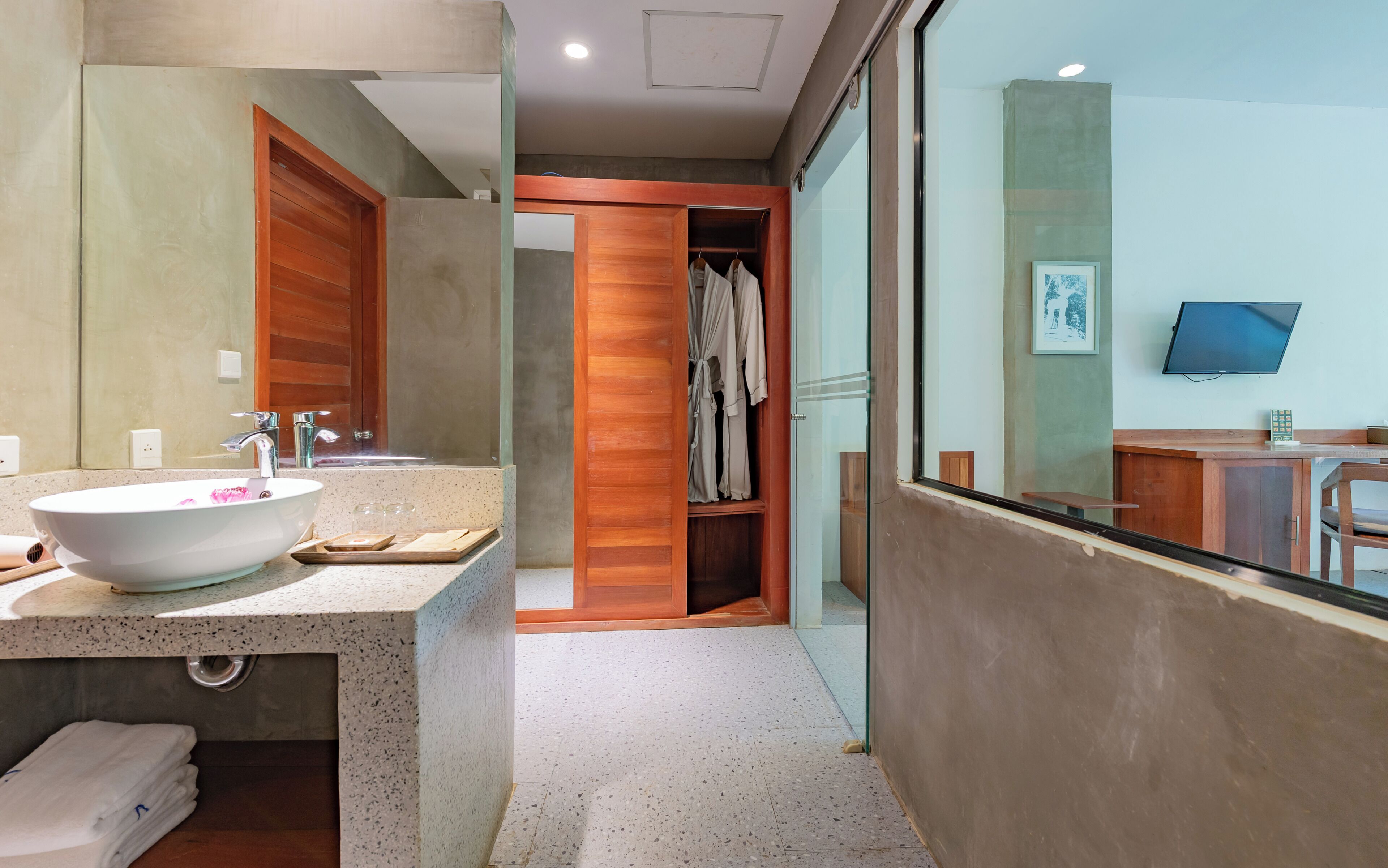 A modern bathroom with a large sink, a mirror, and a wooden vanity.