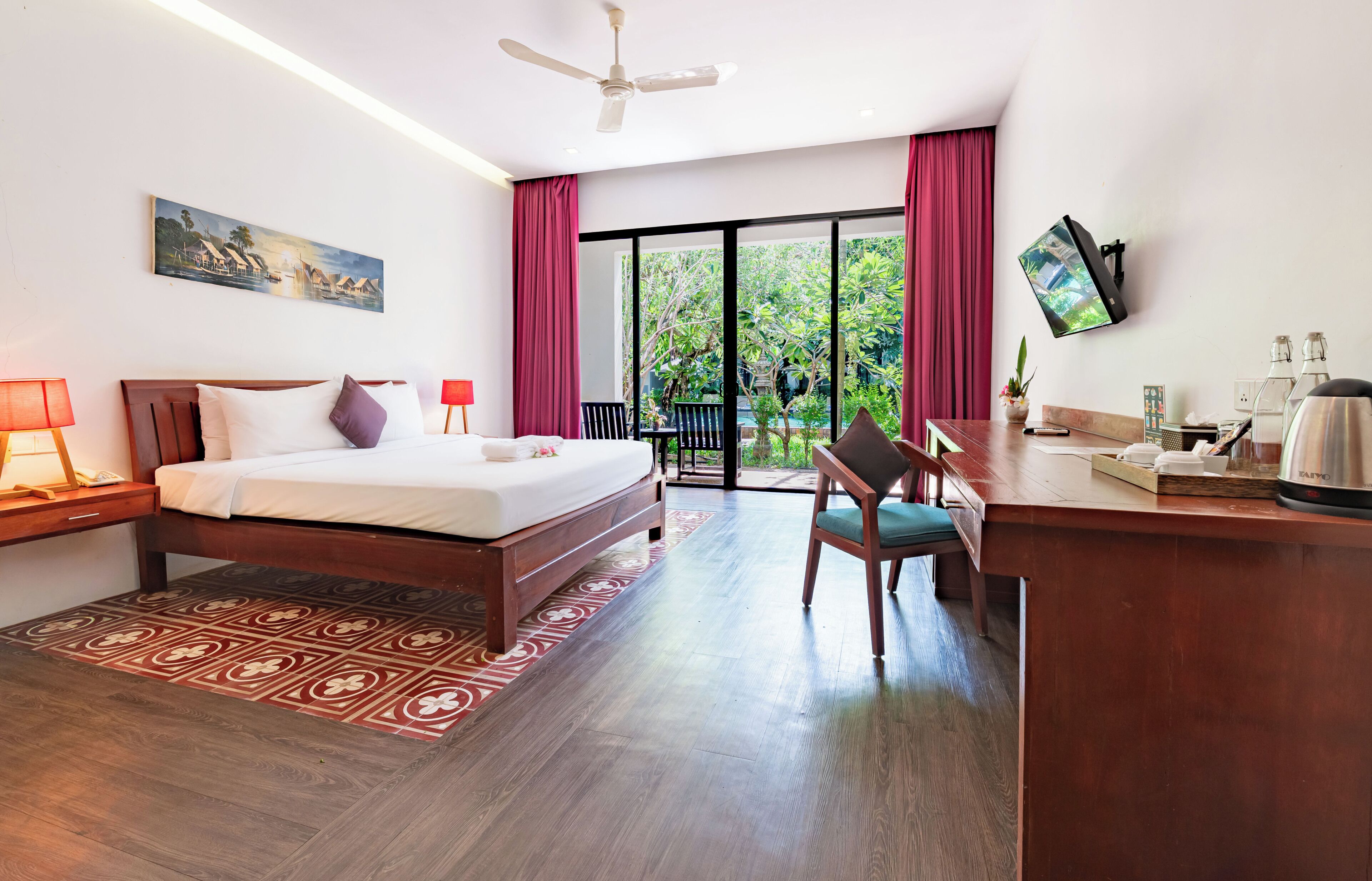 Habitación de hotel con cama, escritorio, silla y vistas a zonas verdes.