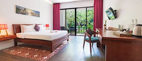 Habitación de hotel con cama, escritorio, silla y vistas a zonas verdes.