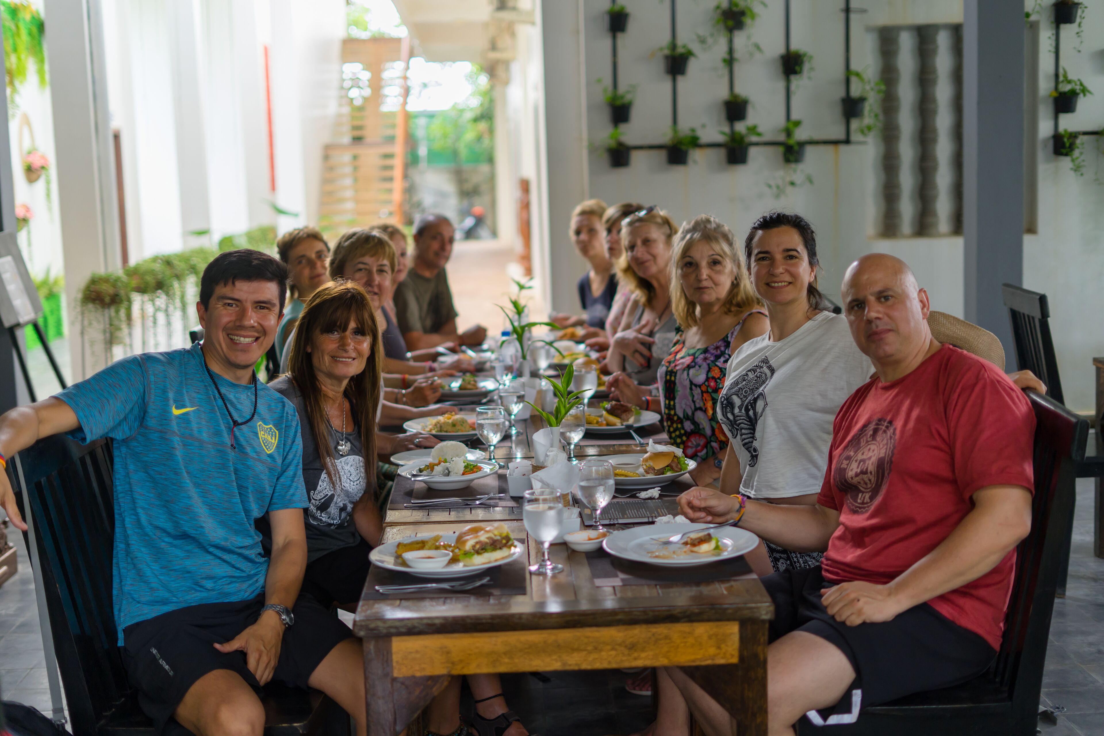 A group of people seated around a wooden table with plates of food and glasses of water.
