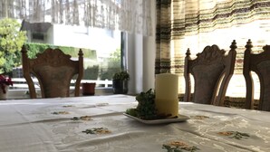 A dining table with a white tablecloth, a candle, and a small plate with greenery. - Pension Falter (Nideggen)