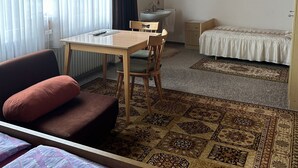 A cozy room with a wooden ceiling, a bed, a small desk with a chair, a bedside table, and a window with sheer curtains. - Pension Falter (Nideggen)