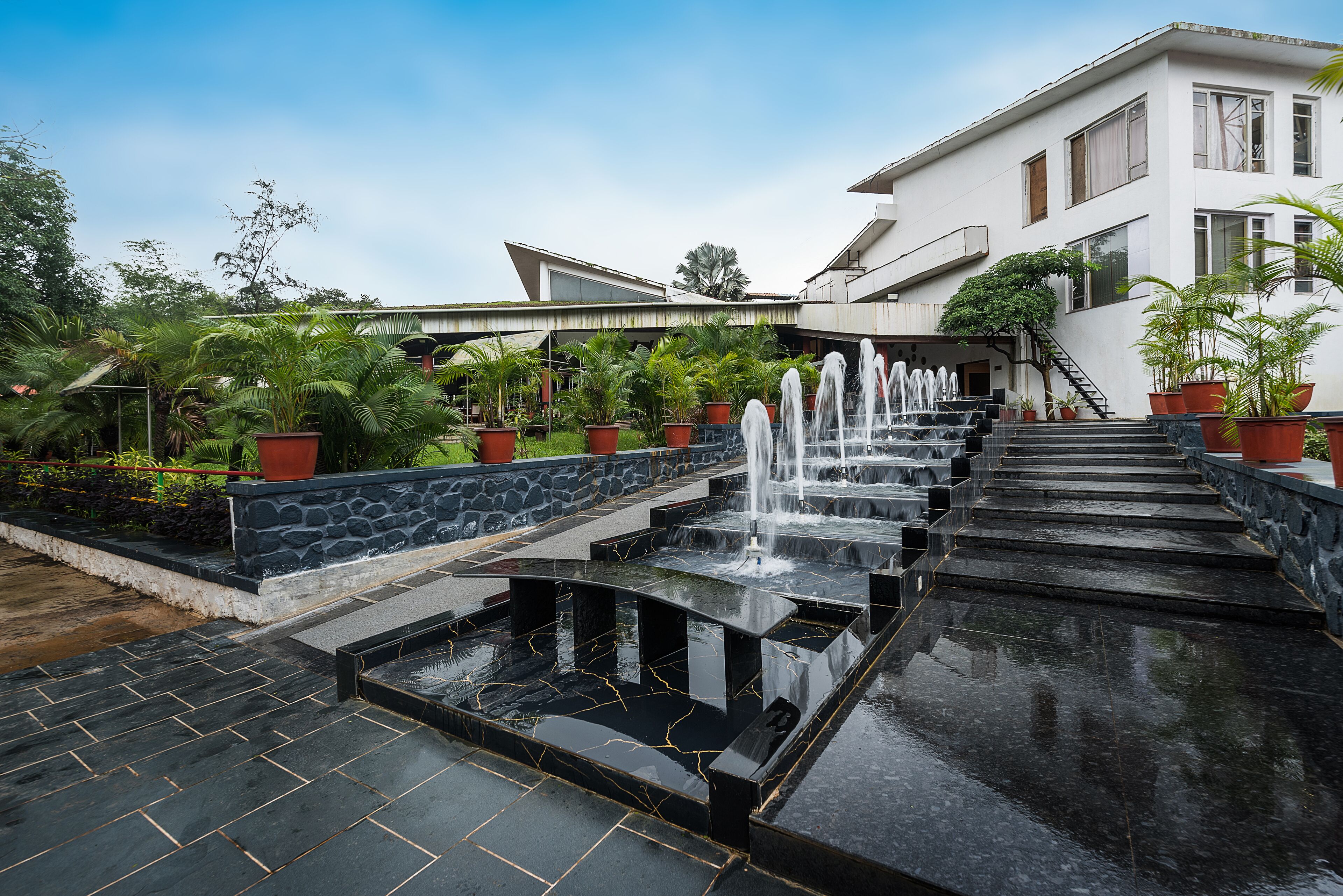 A modern building with a fountain and steps leading to a covered area.