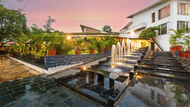 A modern hotel with a stone and glass facade, a fountain, and a well-maintained garden. - Manas Lifestyle Resort Igatpuri (Igatpuri)