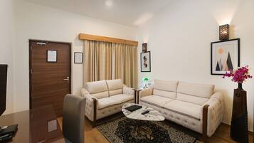 A living room with two sofas, a coffee table, a TV, and a door with a notice.