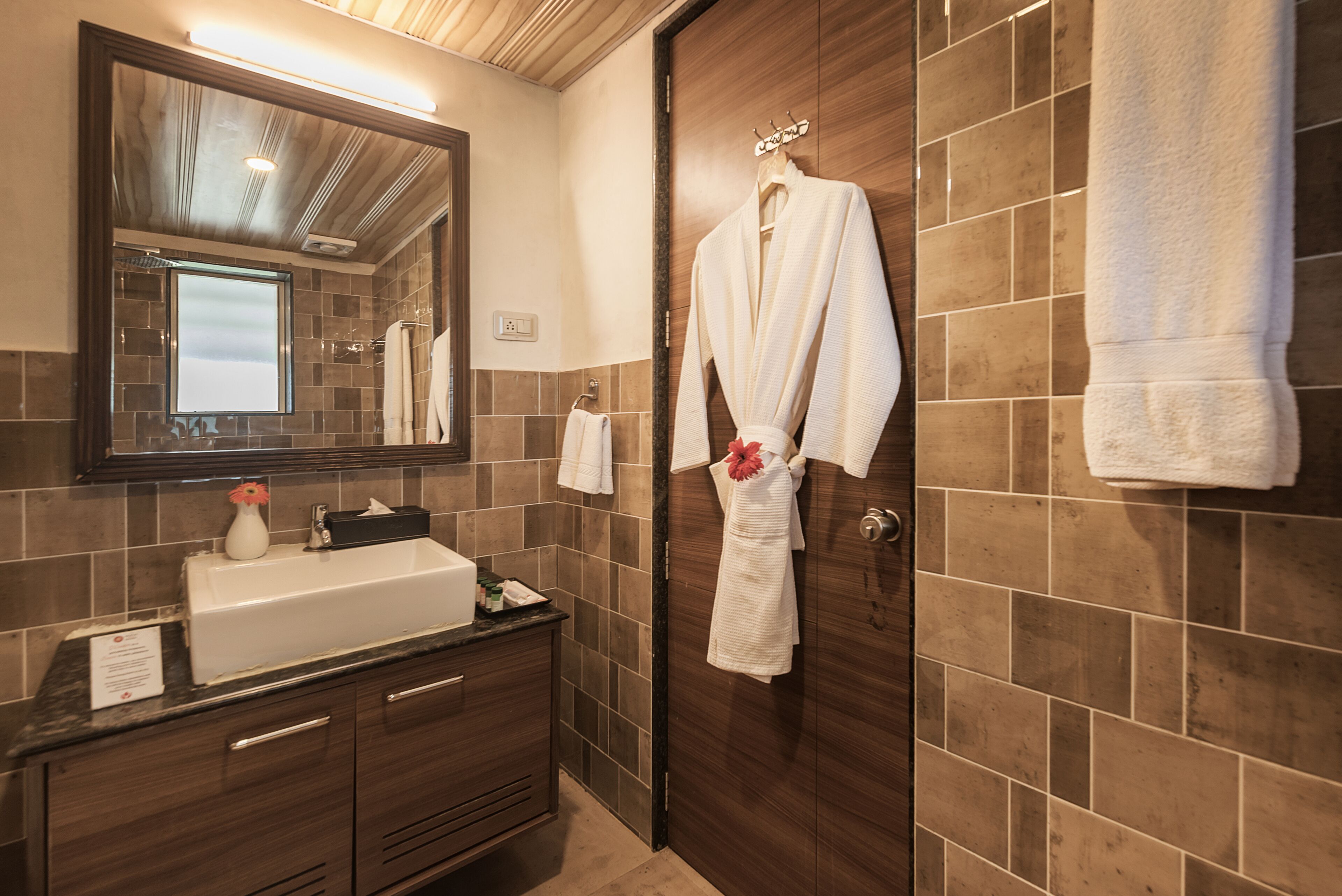 Un baño con tocador de madera, un espejo grande y un perchero con varias toallas.