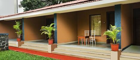 A covered outdoor area with steps leading to a door, potted plants, and a table with chairs.