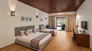A hotel room with two beds, a desk, a chair, a TV, and a balcony with curtains. - Manas Lifestyle Resort Igatpuri (Igatpuri)