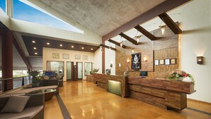 A spacious lobby with a reception desk, seating area, and a view of the sky through a skylight. - Manas Lifestyle Resort Igatpuri (Igatpuri)