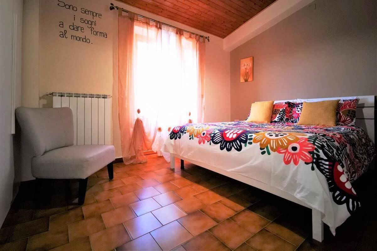 A bedroom with a bed, a chair, a radiator, and a wall with a quote.