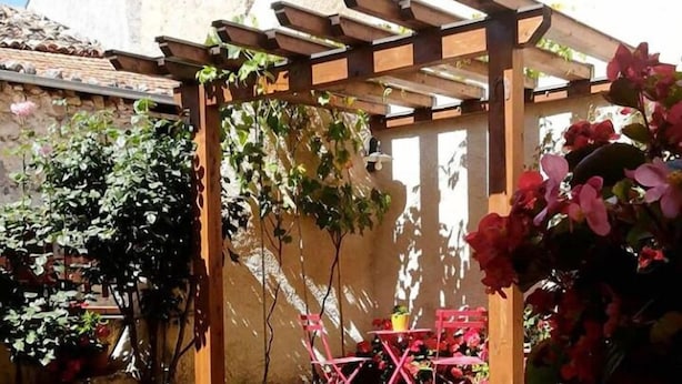 Une terrasse avec une table mise pour le petit-déjeuner, comprenant une assiette de biscuits, un verre de jus de fruits et une tasse.