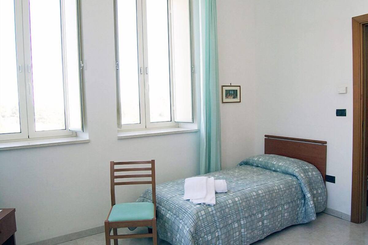 A room with a bed, a chair, and a window.