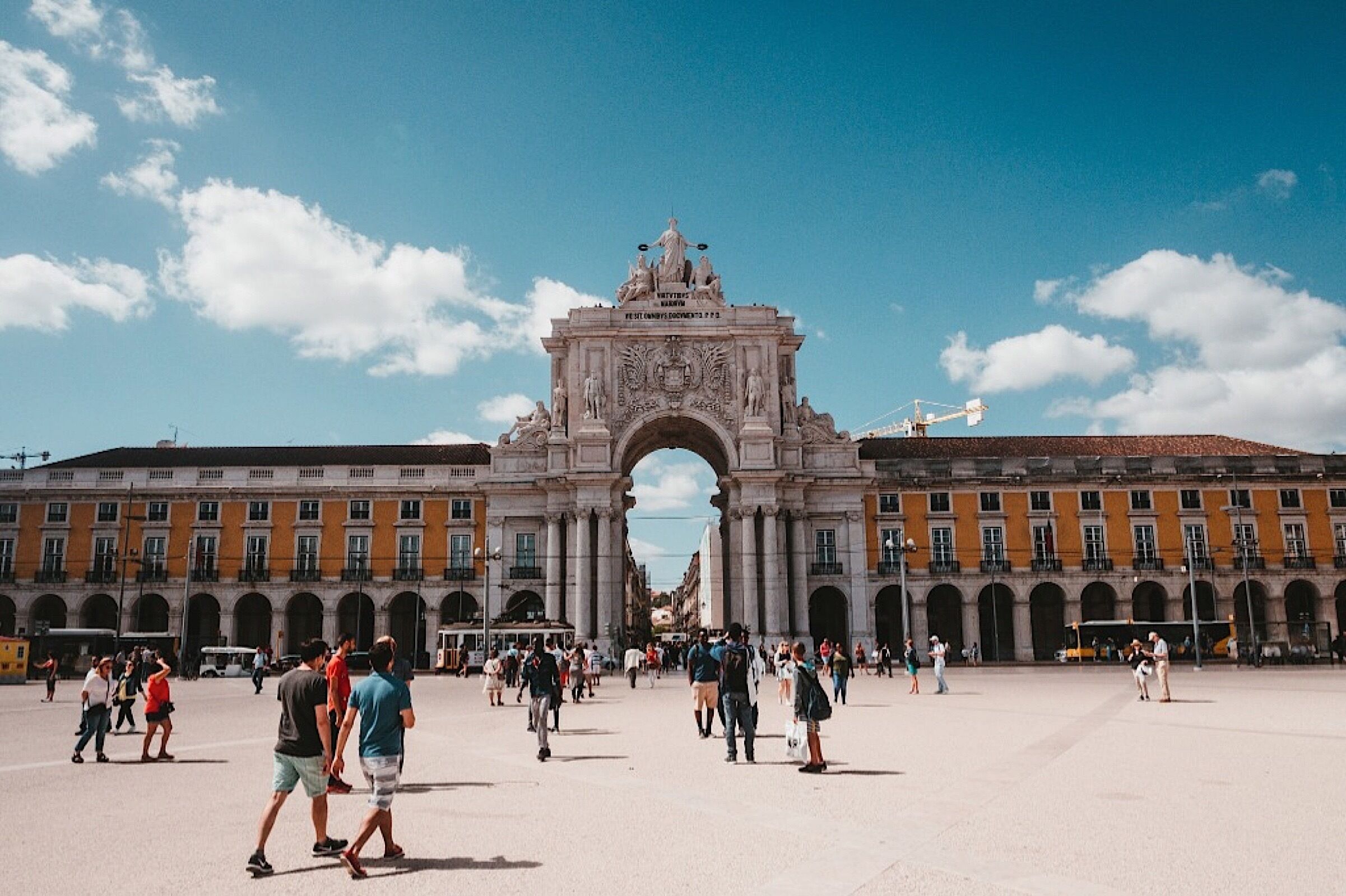 Una plaza histórica con un arco ornamentado, rodeada de edificios clásicos con ventanas y balcones de arco.