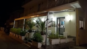 A hotel entrance with a balcony, potted plants, and a sign indicating it is a hotel. - Hotel Mon Reve (Rimini)