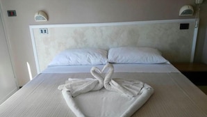 A hotel room with a neatly made bed, a headboard with a light switch, and a bedside telephone. - Hotel Mon Reve (Rimini)