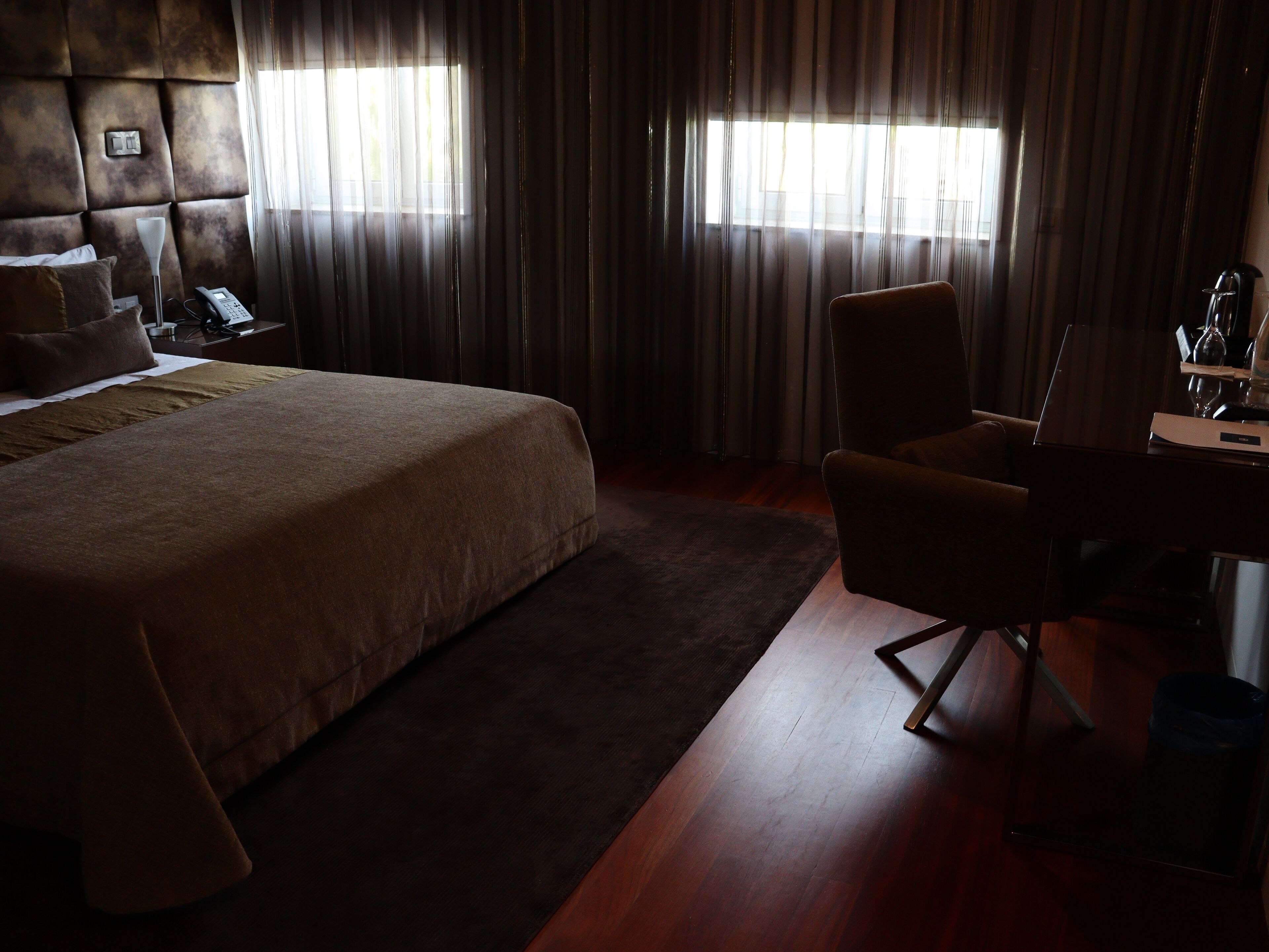 A hotel room with a large bed, a desk, a chair, and a telephone.