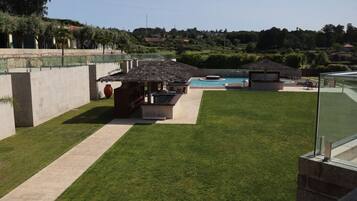 A backyard with a swimming pool, a barbecue area, and a patio with seating.