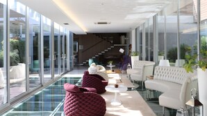 A modern interior with glass walls, a glass pool, and contemporary furniture. - FH Hotel (Felgueiras)
