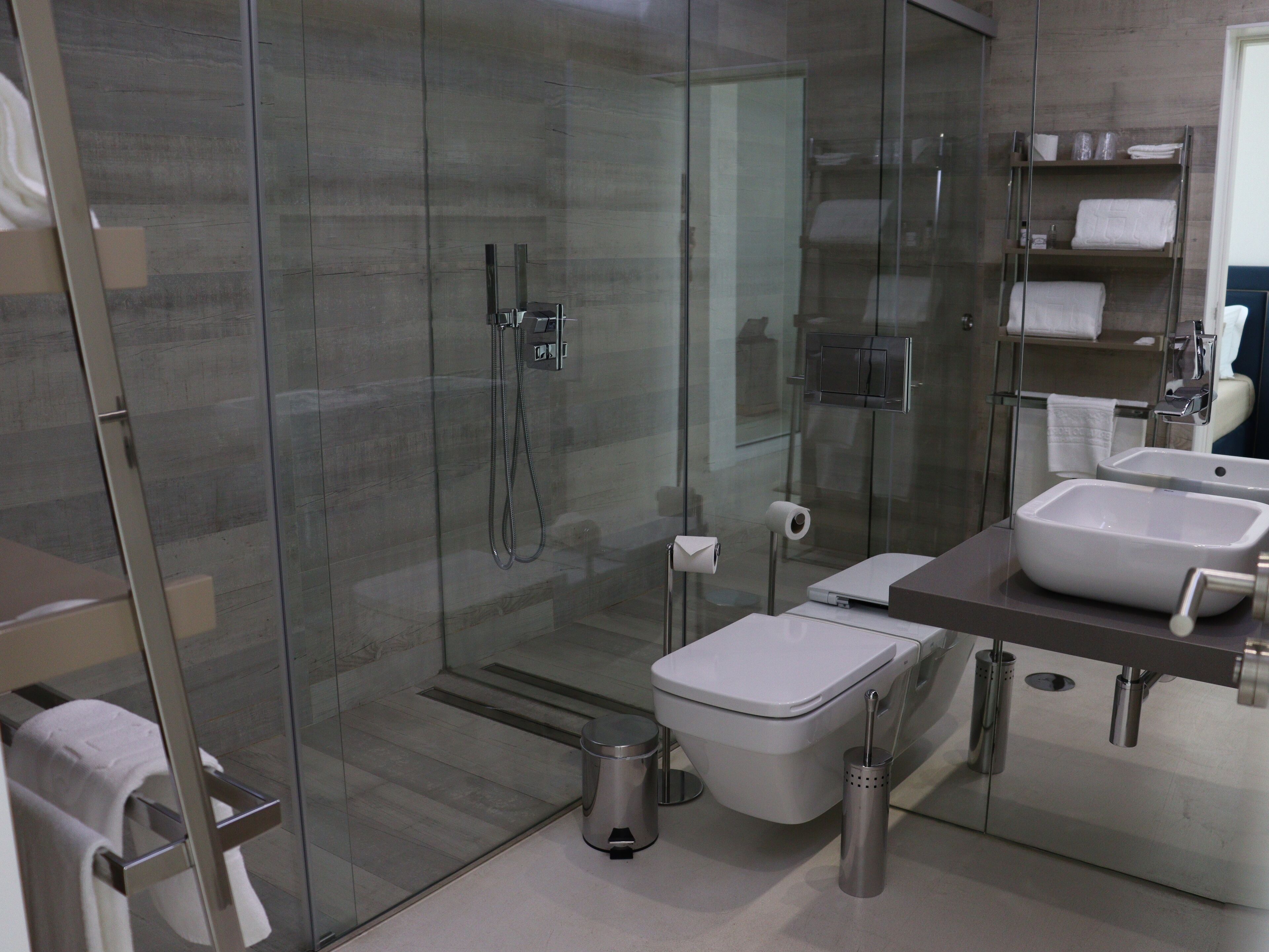 A modern bathroom with a glass-enclosed shower, a toilet, a bidet, and a sink with a mirror.