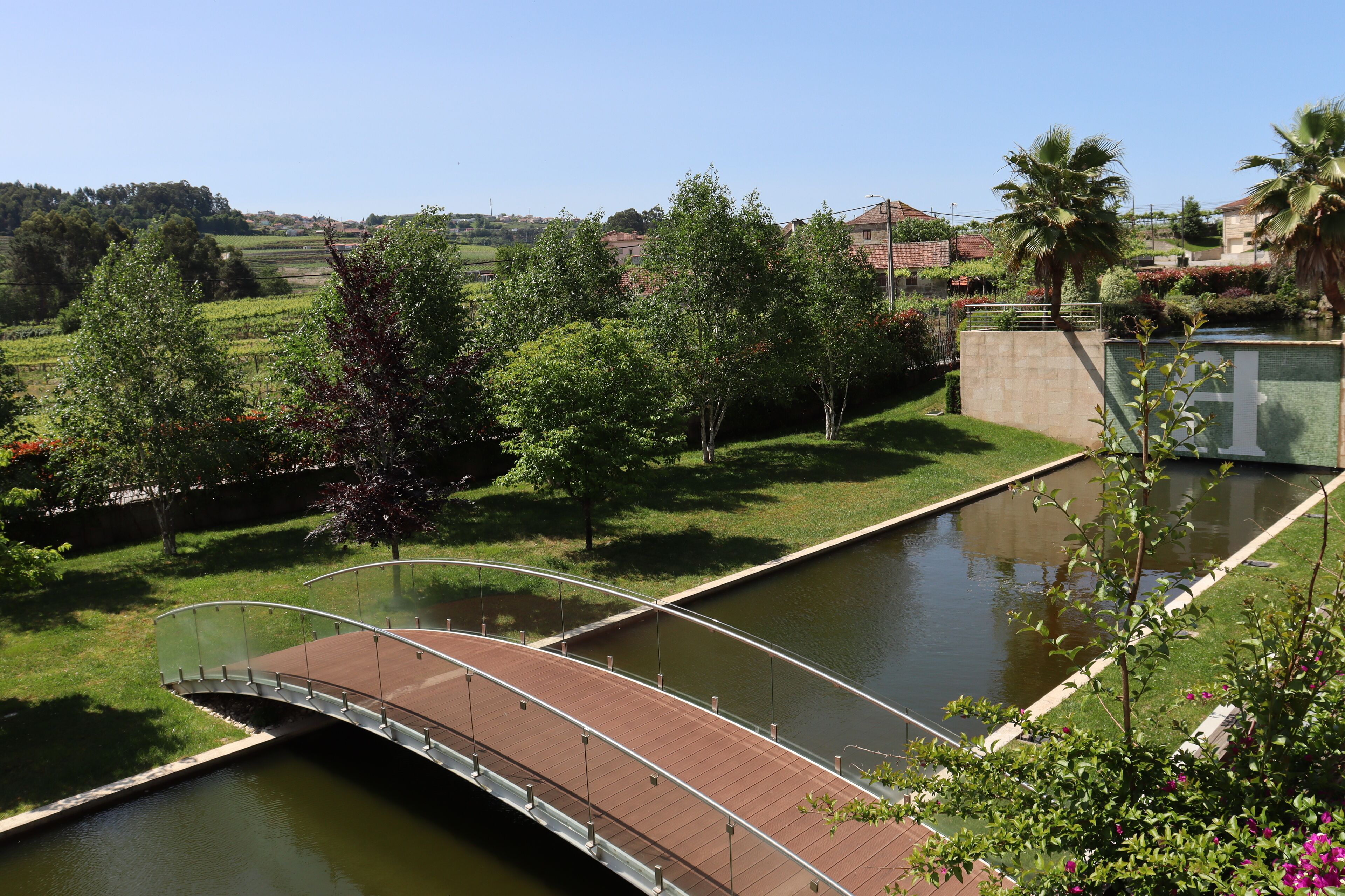 Un pont sobre un canal amb una zona verda i arbres a ambdós costats.