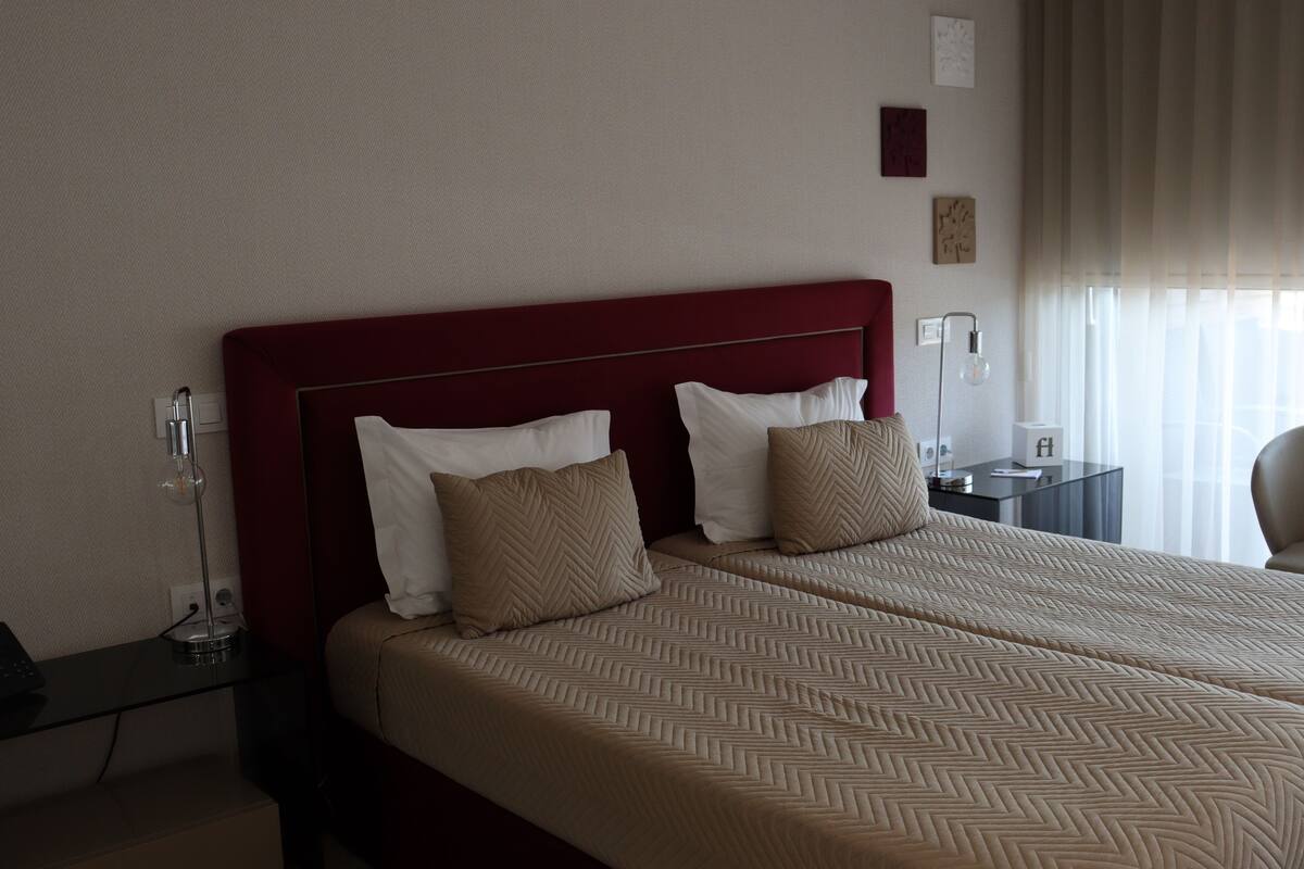 A hotel room with a large bed, two bedside tables, a desk, and a chair.