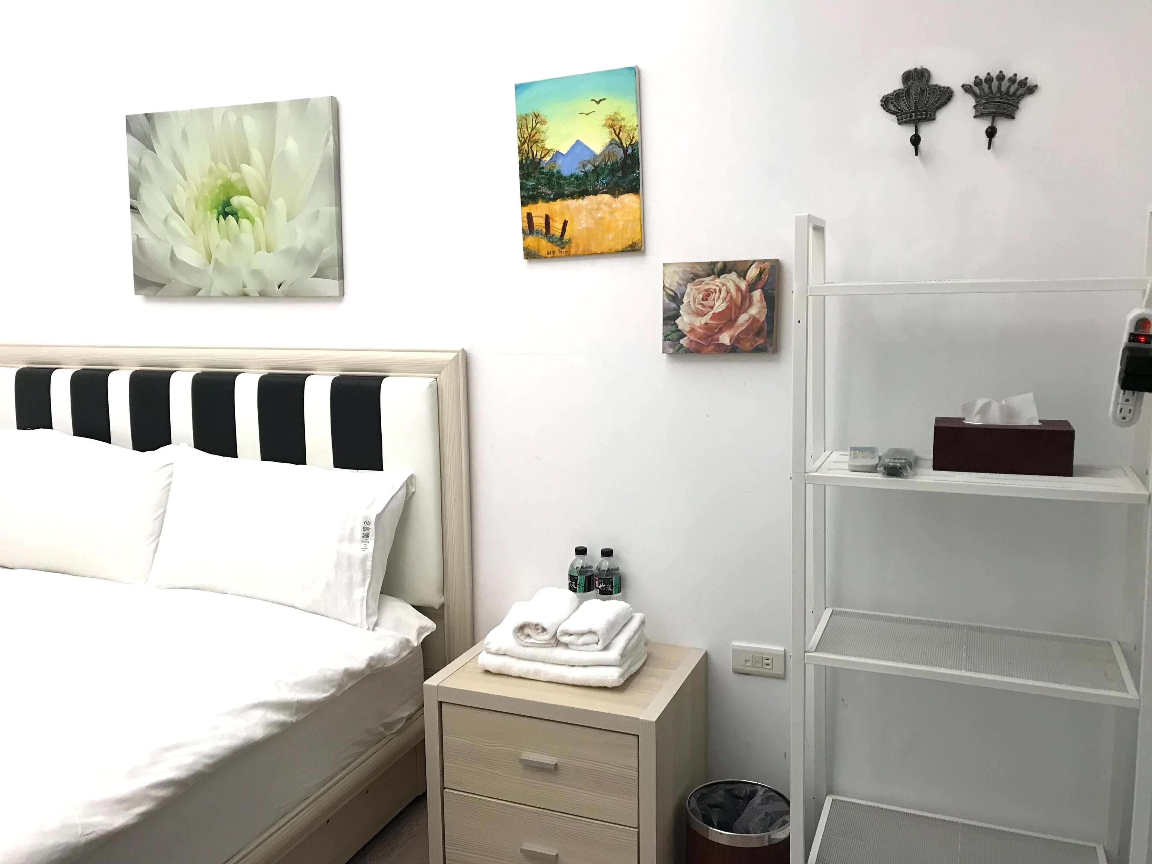 A neatly arranged hotel room with a bed, bedside table, and wall-mounted artwork.