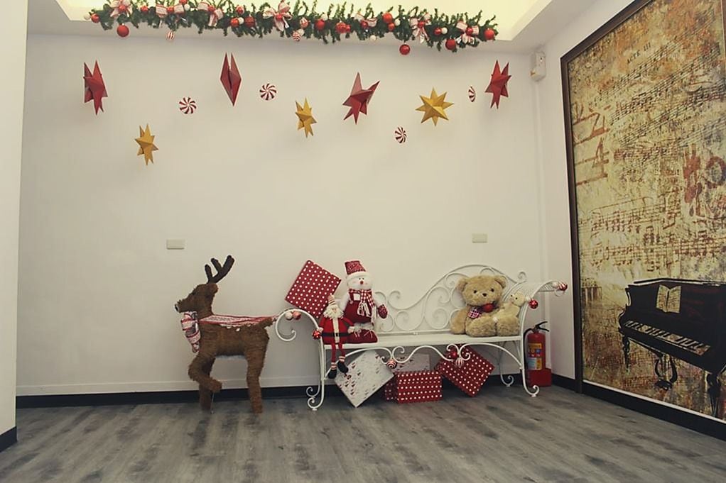 Um quarto com um banco branco, um urso de pelúcia, um veado e enfeites de Natal.
