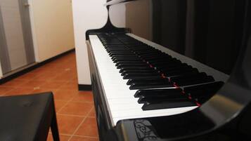 A piano with a black and white keyboard, a bench in front, and a tiled floor.